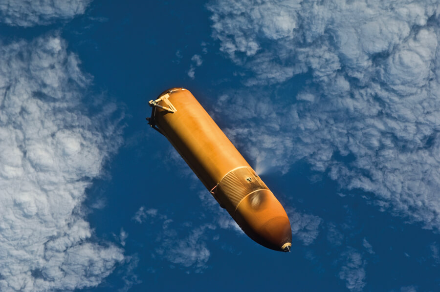 Backdropped by a blue and white part of Earth, the STS-131 external fuel tank (ET) begins its relative separation from the Space Shuttle Discovery following launch.