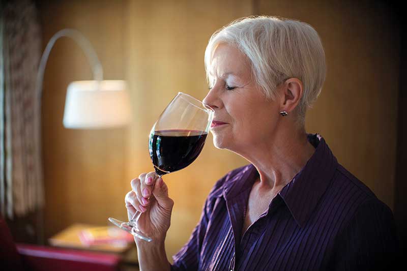 Woman smelling and tasting red wine