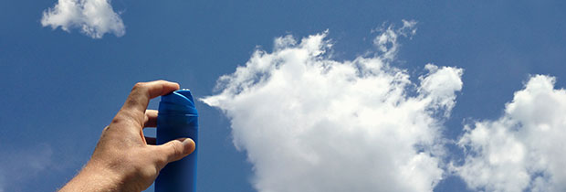 Aerosol can being sprayed to make clouds in the blue sky