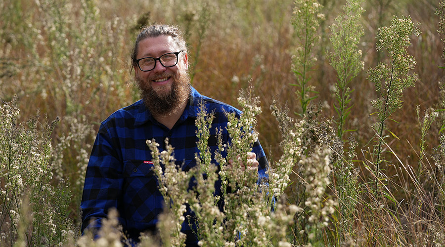 Dr Ben Gooden, CSIRO research scientist, surrounded by fleabane weed. Image: GRDC
